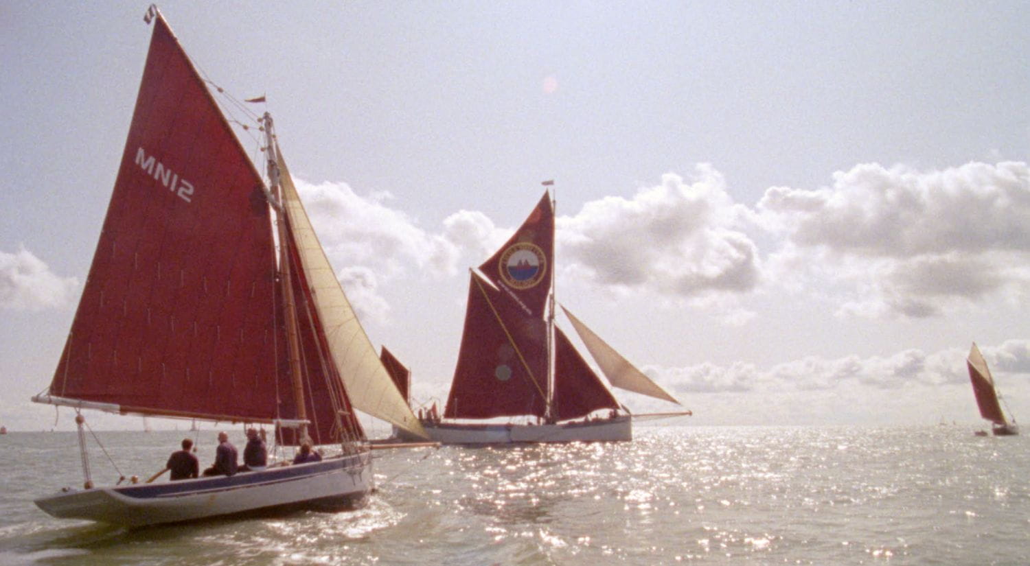 Sailing boats sail on a sun dappled river