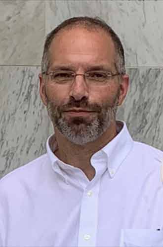 Professor Wayne Martin wearing a white shirt and wire-rimmed glasses