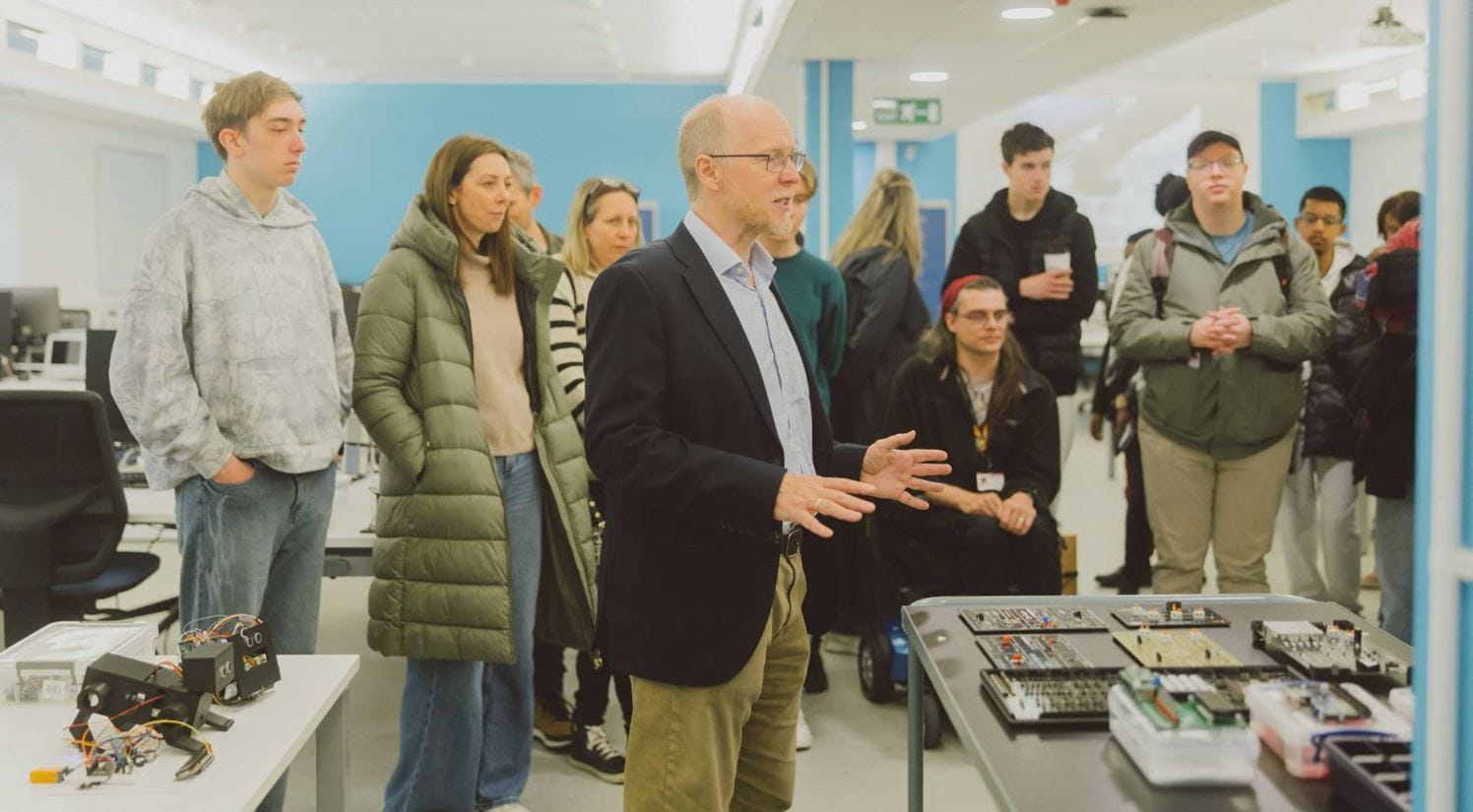A group of people listening to a lecturer giving a talk in a laboratory.