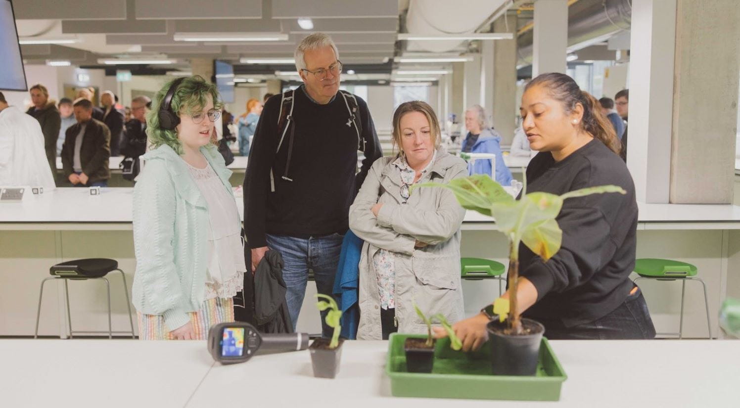 A small group of people listening to a lecturer talking about plants.