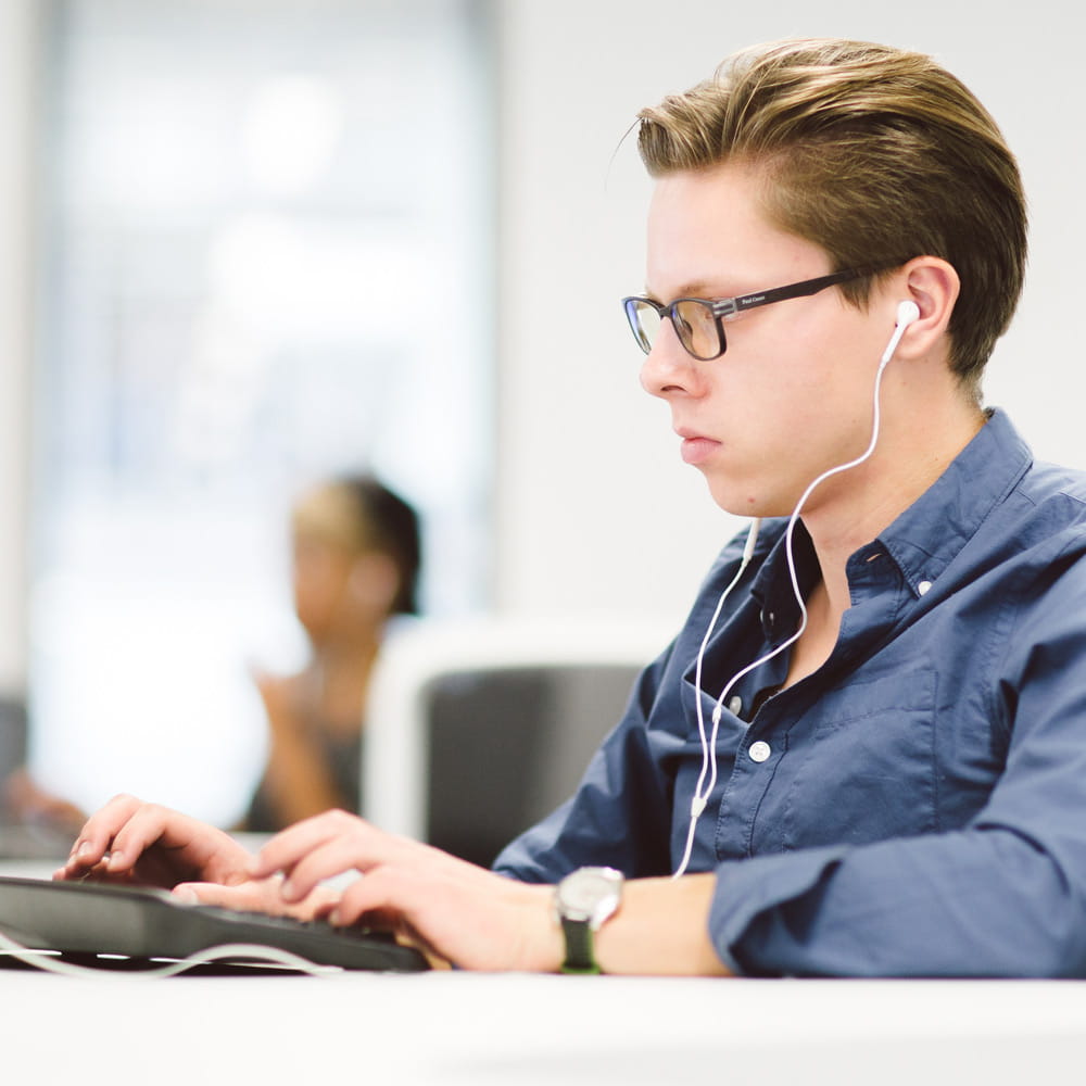 Young man using a computer, wearing headphones