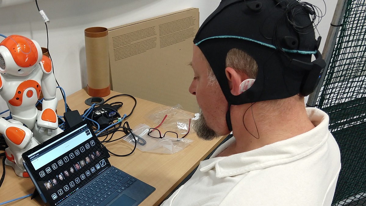 Professor Reinhold Scherer wearing an EEG cap looking at a laptop screen displaying letters in large squares.