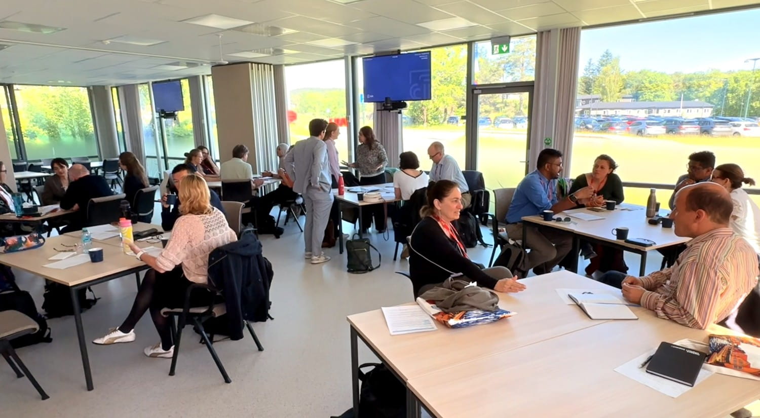 A large room with people sitting at tables, talking.