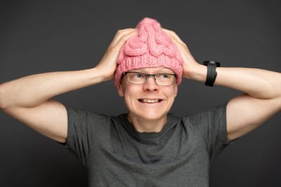 Nat Hawley wearing a pink knitted hat, with his hands on his head.