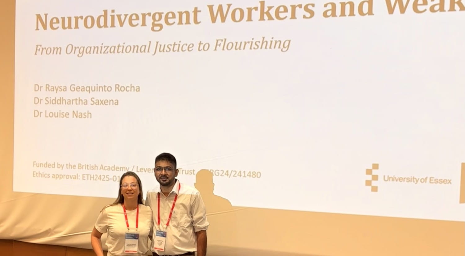 Dr Raysa Rocha and Dr Siddhartha Saxena standing in front of a screen showing the title slide for their presentation.