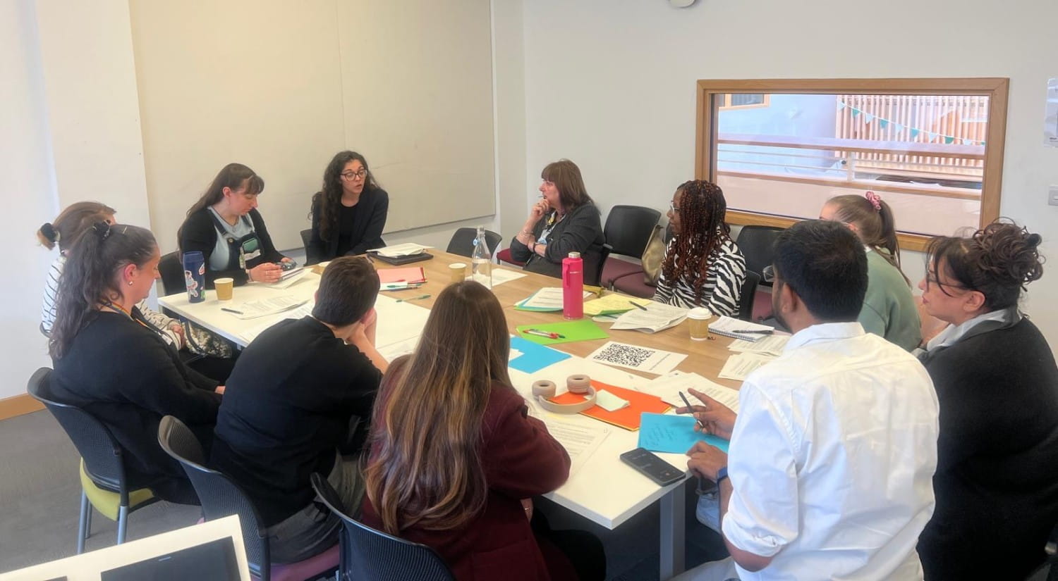 A group of people sitting around a table covered in papers.