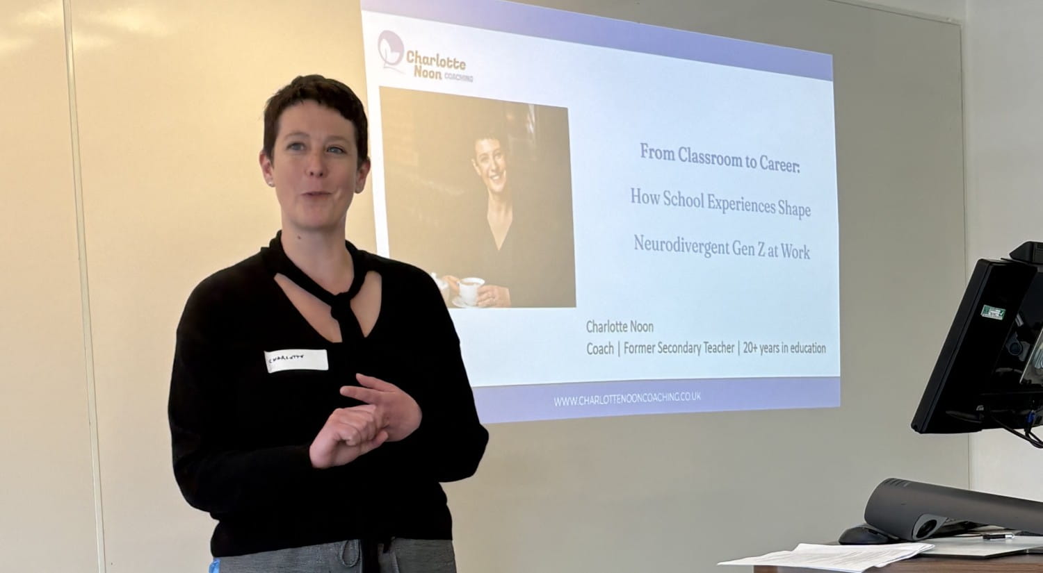 Charlotte Noon standing in front of a screen with talk slides projected on to it.