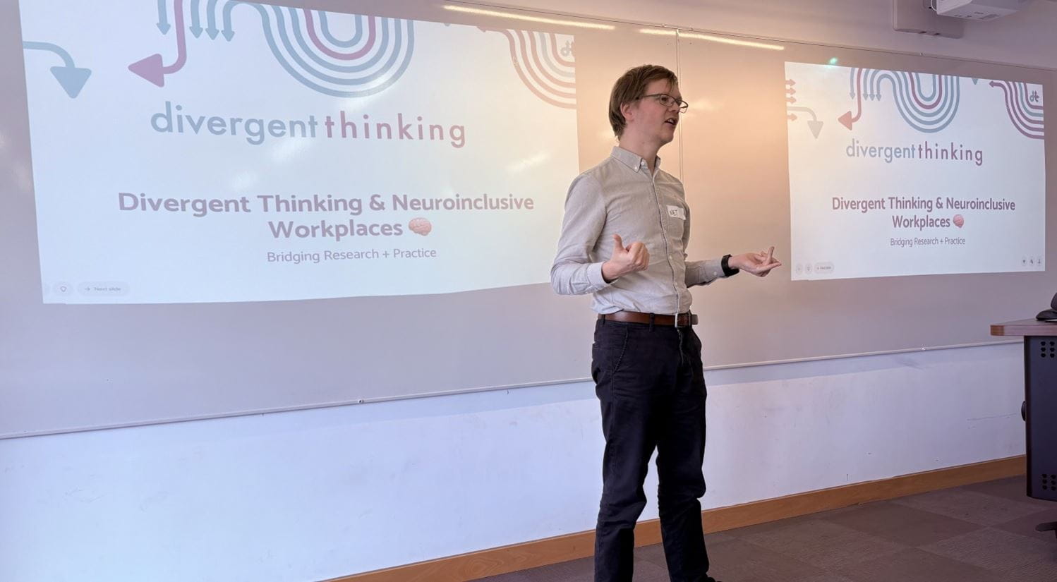 Charlotte Noon standing in front of a wall with talk slides projected on to it twice.