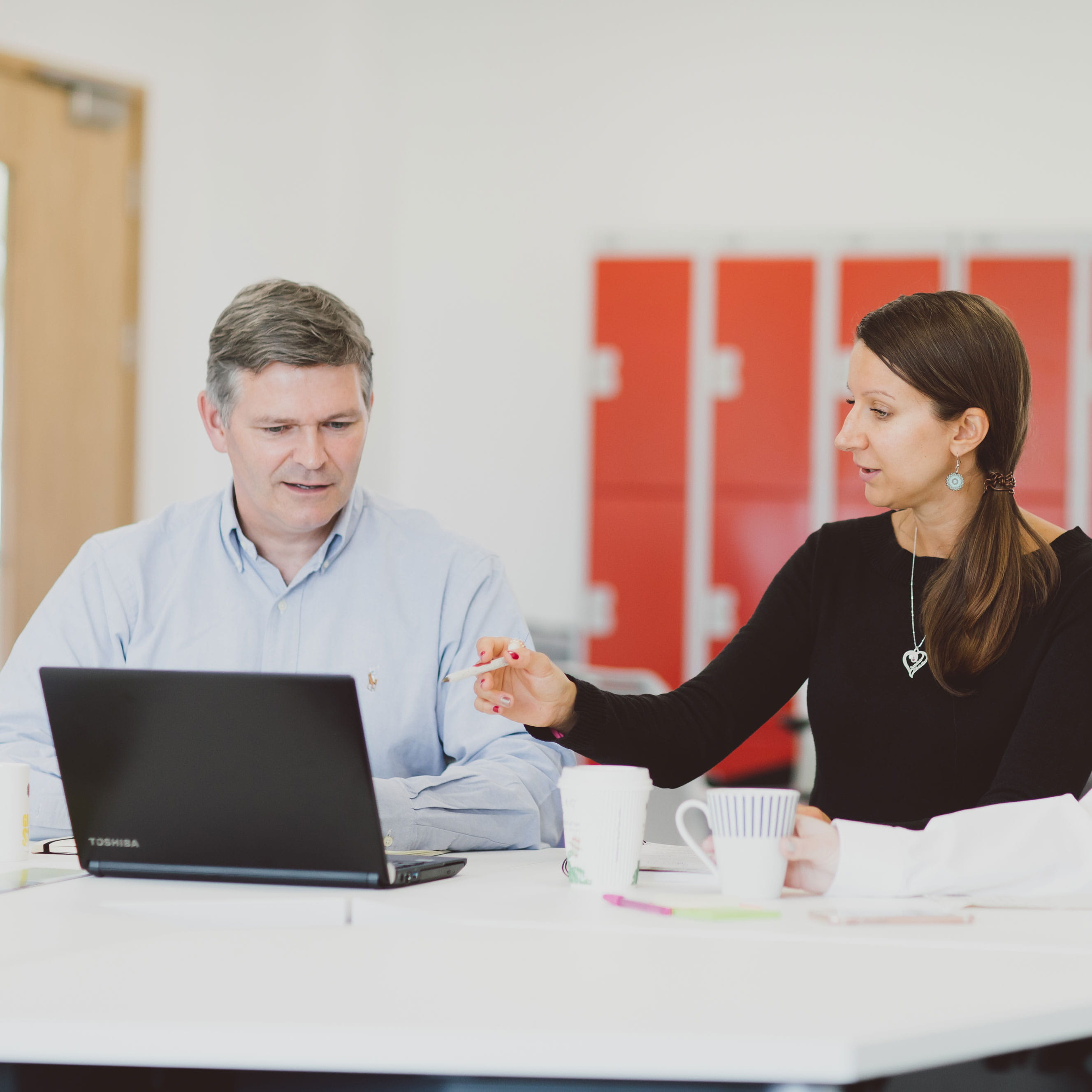 Staff talking to each other in front of a laptop