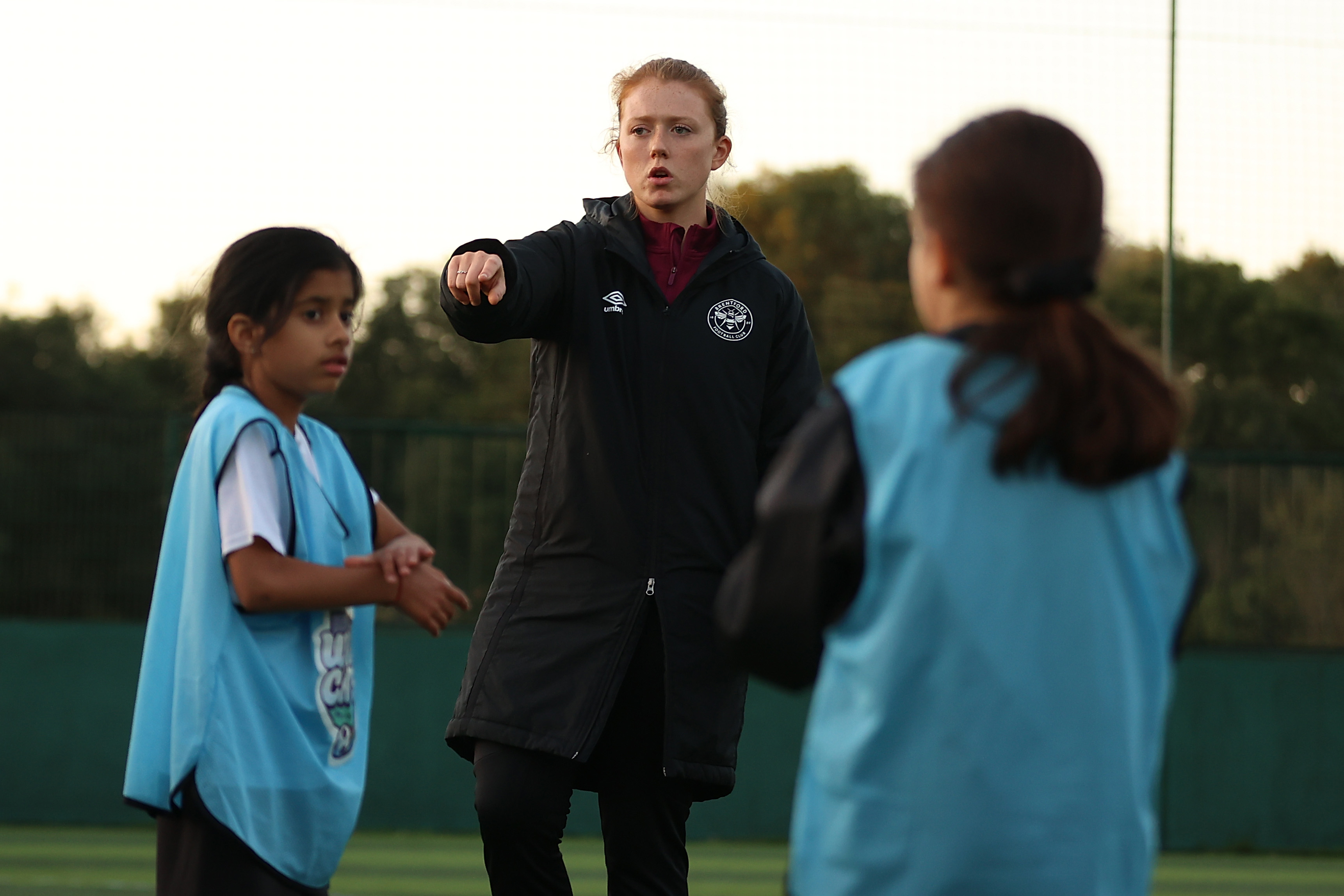 Female football coach, coaching two students 