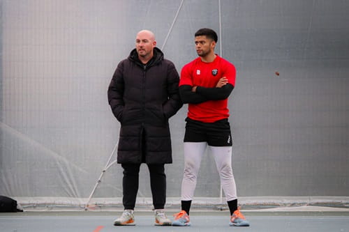 University of Essex Performance Tennis Coach Nigel Parsons standing with men's first team player Victor Chaw in conversation at Essex's tennis courts and all-weather bubble
