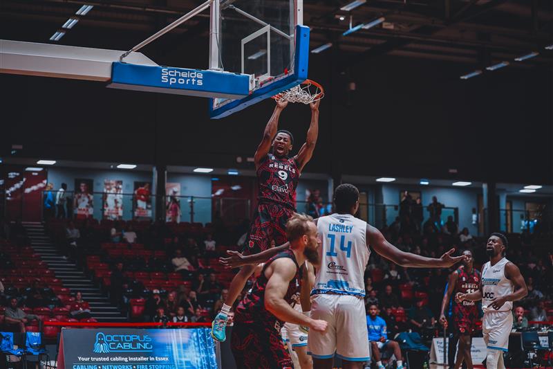 Rebels player jumping up to basket ball hoop during a match
