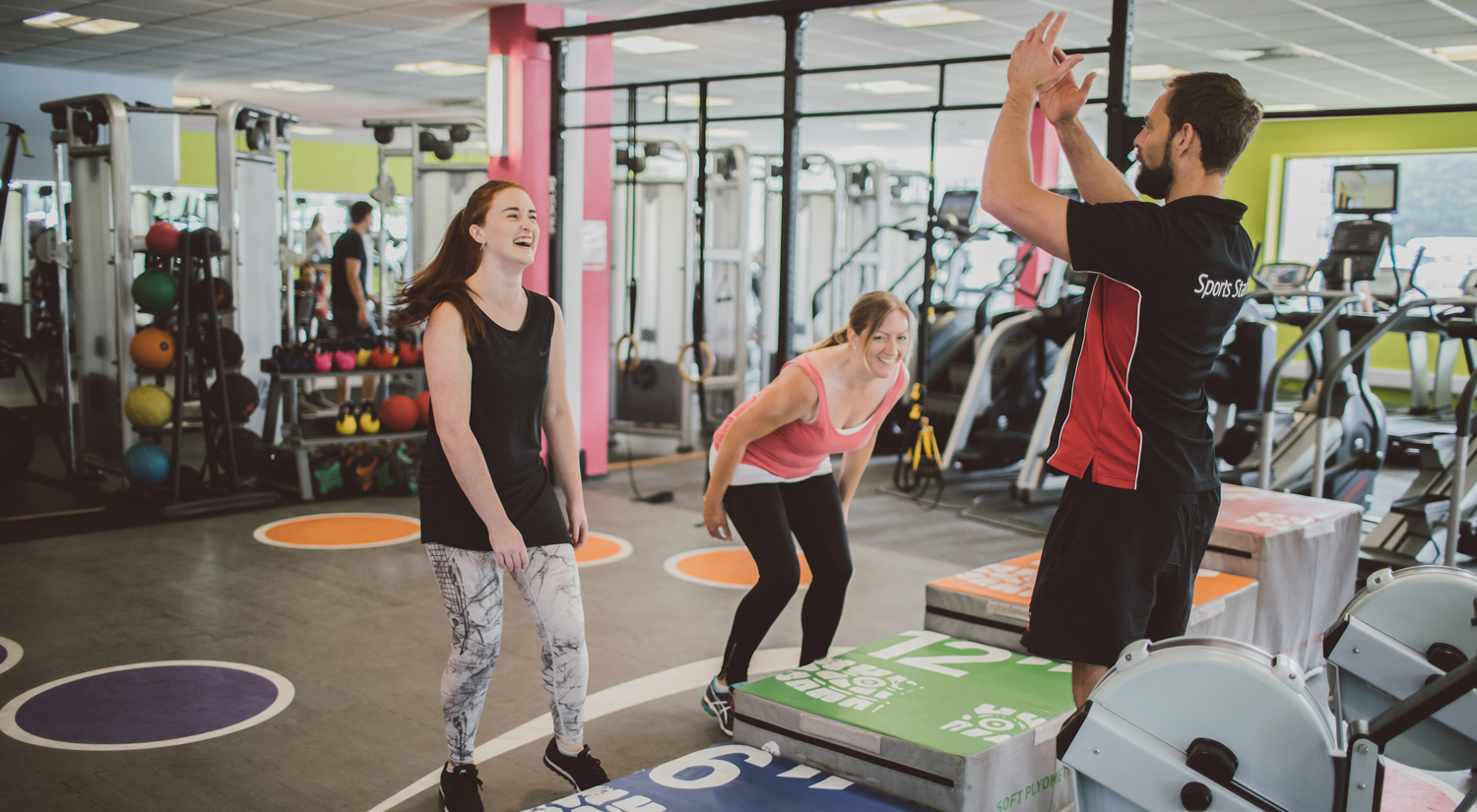Personal trainer training two people in a gym
