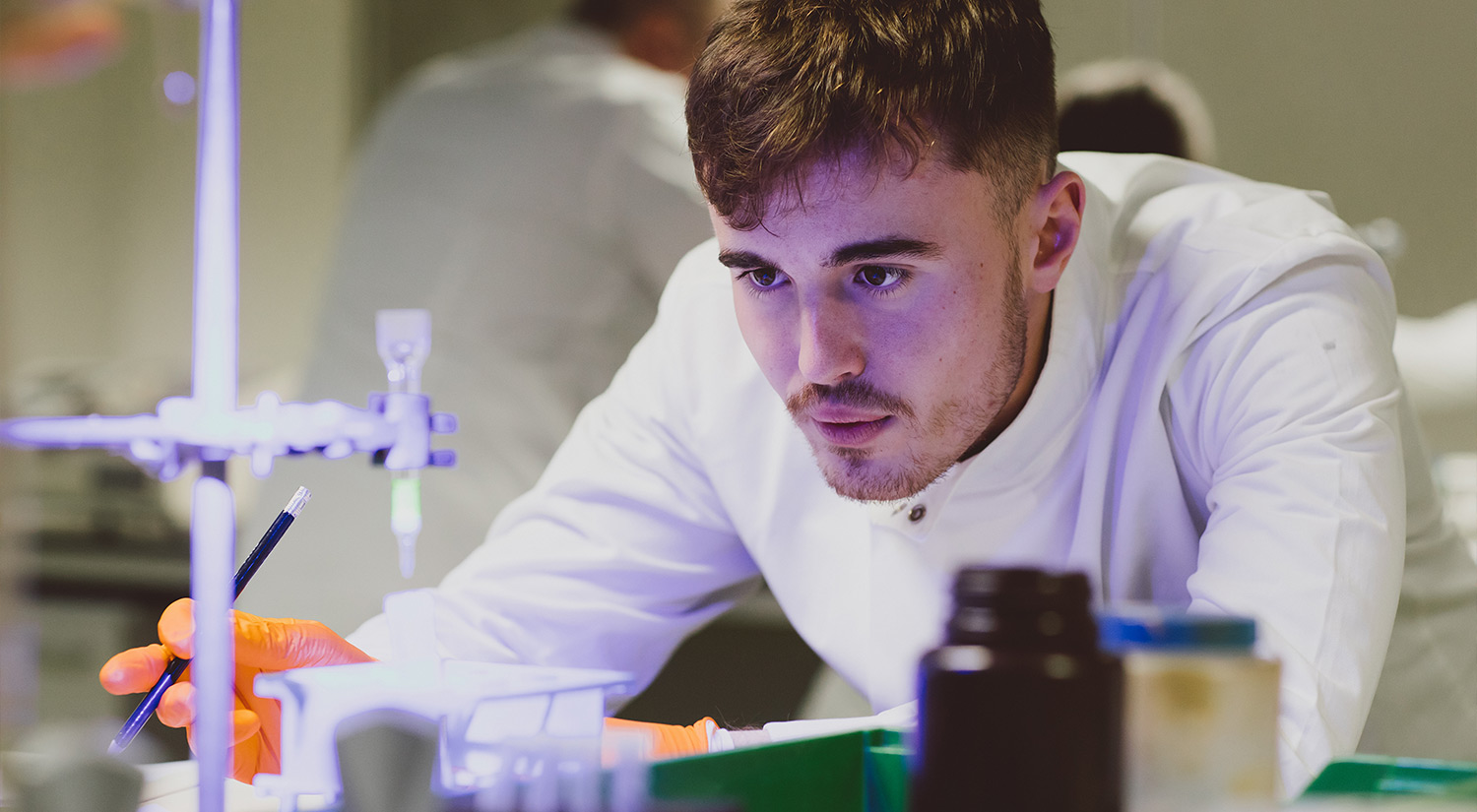 Student in a lab coat performing an experiment