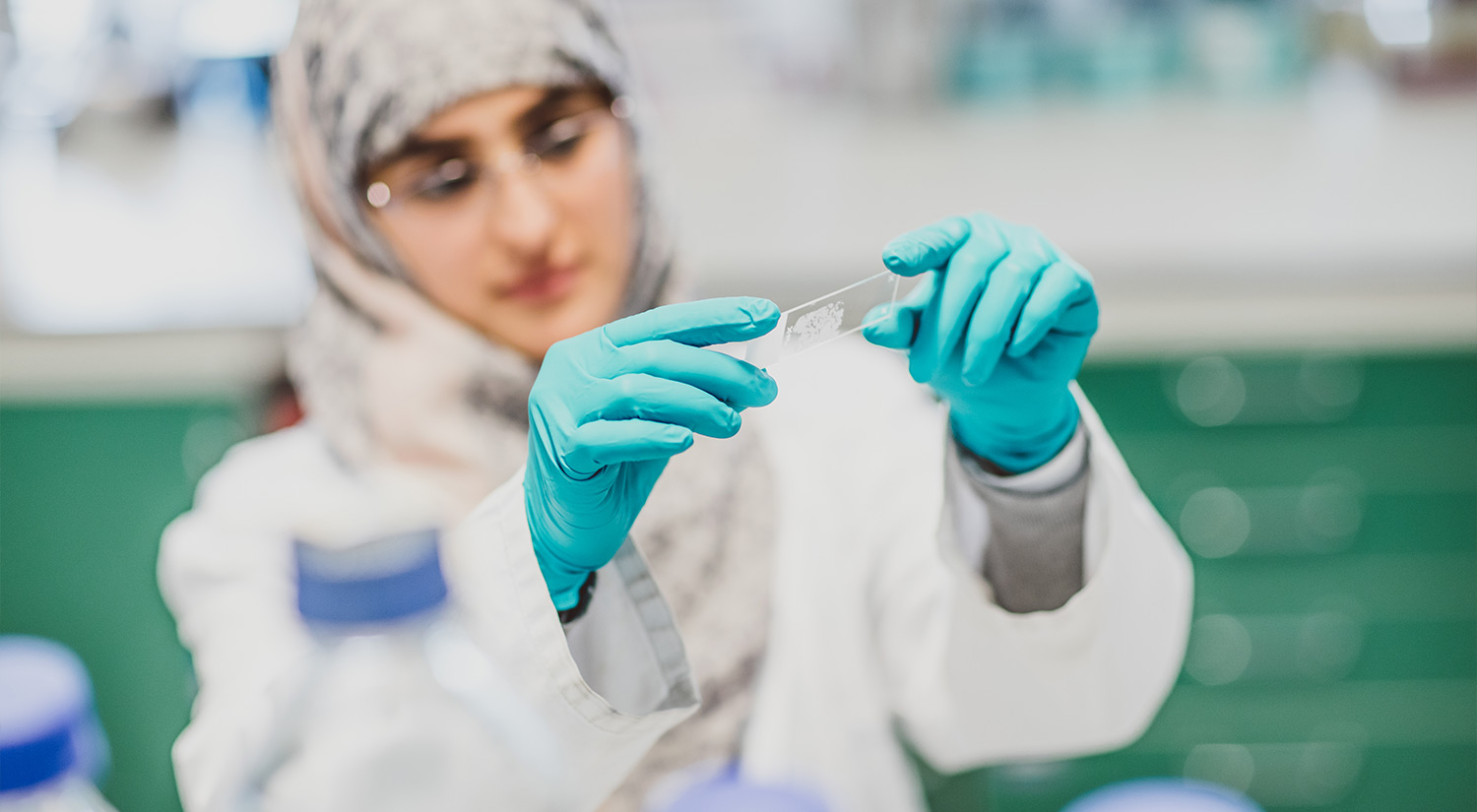 Student in a research lab looking at a glass slide