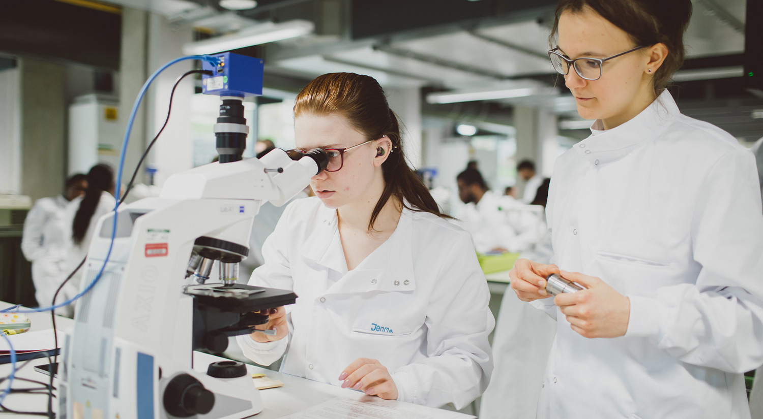 Two students in a STEM Lab using a microscope