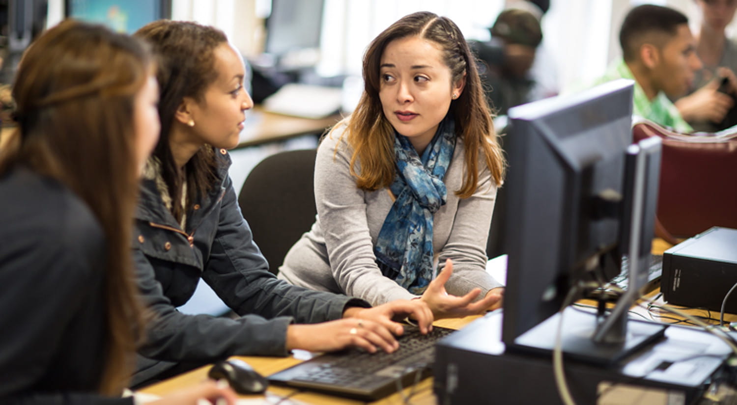 Image of three female students discussing work in a PC lab