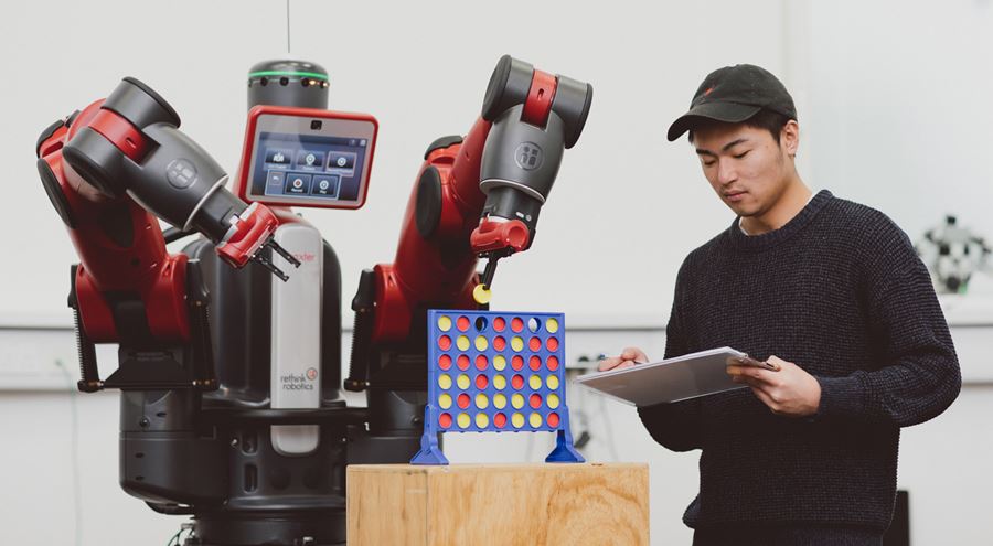 Image of a male student playing a game of Connect 4 with a Baxter robot whilst analysing its performance