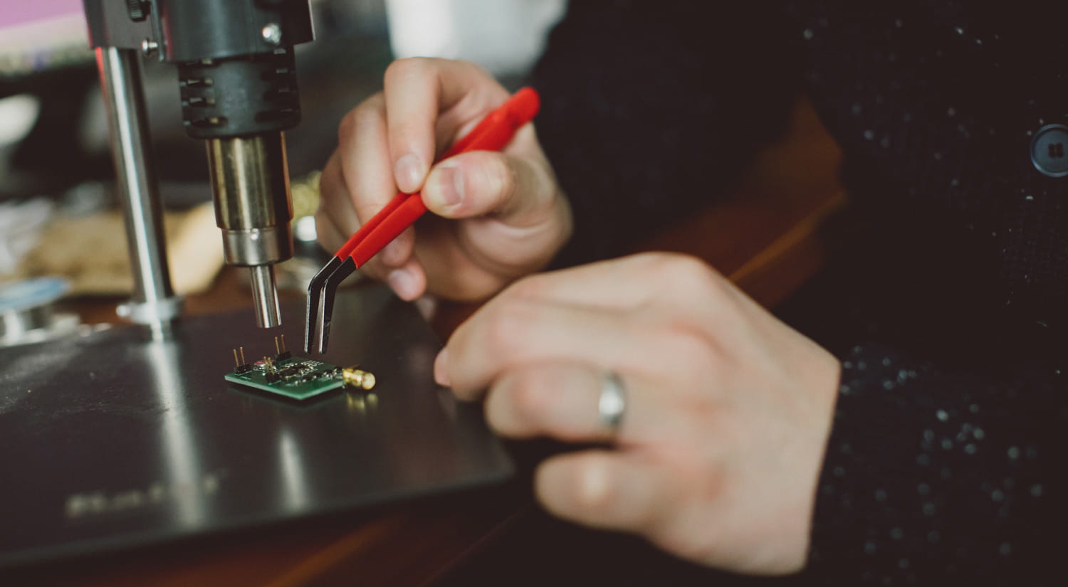 A close-up photo of a student working on a microchip under a microscope