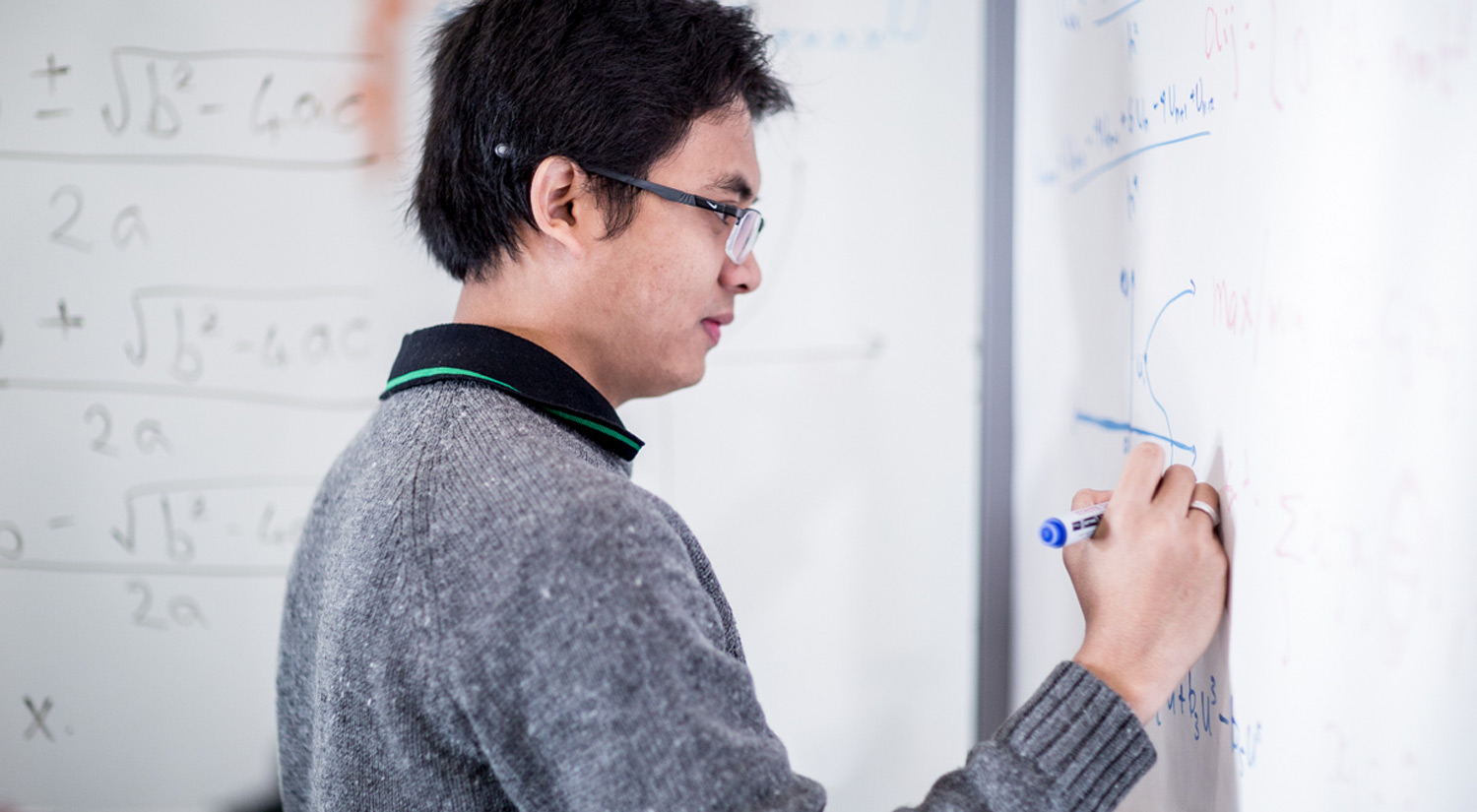 Image of a student working on a white board wall