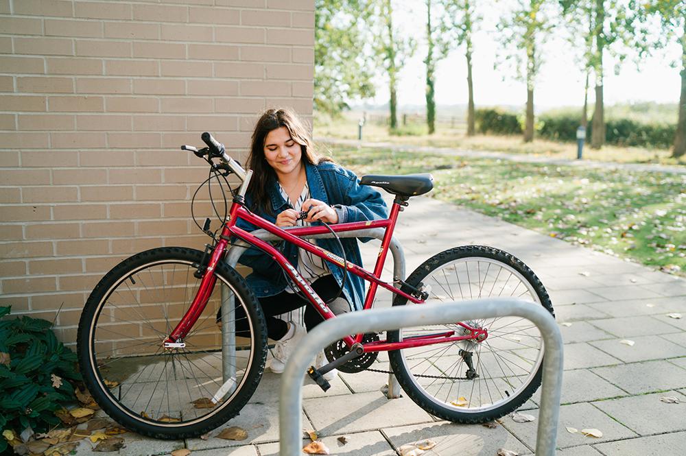 A student locks their bike to a rack outside University accommodation.