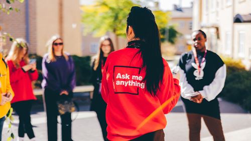 A student ambassador with 'ask me anything?' on her jumper giving a tour to visitors