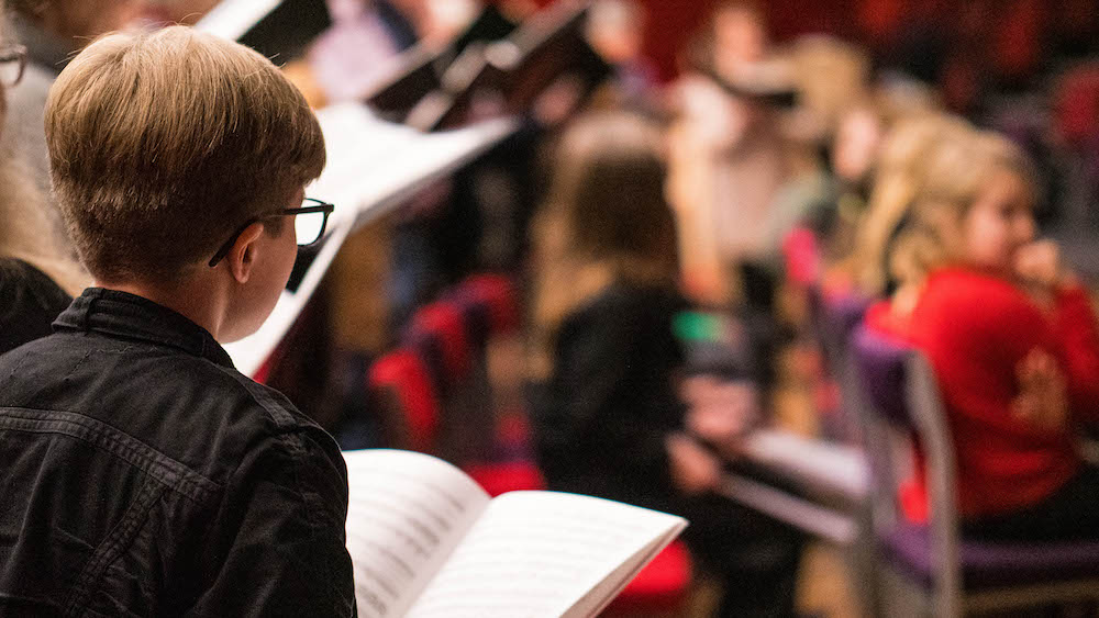 Member of the UoE Choir singing from their sheet music