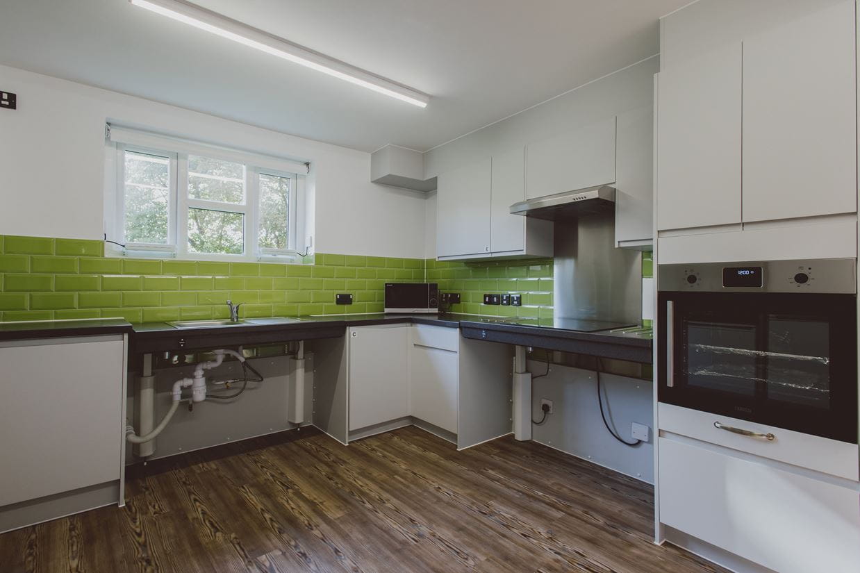 White kitchen with green splashback, showing adapted facilities