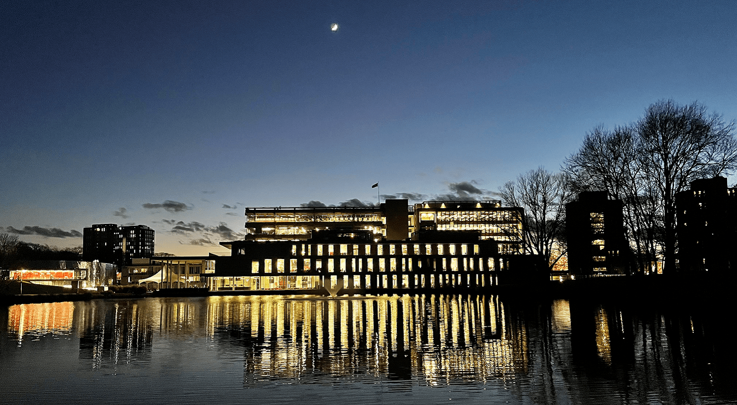 The Silberrad Centre lit up at night in front of the lake